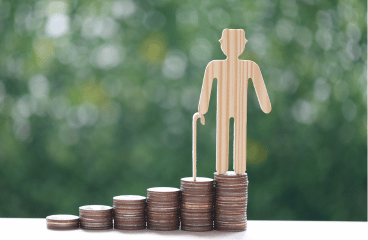 Inwestycje 13 Eine Holzfigur einer Person mit Stock steht auf einem Stapel Münzen und symbolisiert damit finanzielle Stabilität. Daneben befinden sich weitere Münzstapel unterschiedlicher Höhe vor einem verschwommenen grünen Hintergrund. Diese Szene unterstreicht auf subtile Weise die Bedeutung von Immobilienkrediten in der persönlichen Finanzplanung.